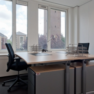 Kantoorruimte huren op Bezuidenhoutseweg 161, Den Haag Haagse Hout. De lichte ruimte heeft een groot raam, twee bureaus met stoelen en een uitzicht op omliggende gebouwen.