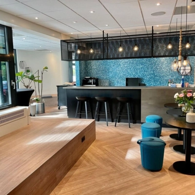 Moderne lounge in kantoorpand op Johan de Wittlaan 3-7, Den Haag Statenkwartier, met zithoek, barkrukken en decoratieve verlichting. Ideaal voor kantoorruimte huren.