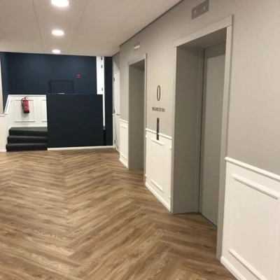 Een moderne, goed verlichte kantoorruimte met houten vloer, twee liften en een trap aan de Johan de Wittlaan 3-7, Den Haag Statenkwartier, ideaal voor kantoren te huur.