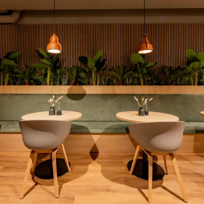 Modern ingerichte kantoorruimte op Diemerhof 42, Diemen met stijlvolle zitjes en houten details. Ideaal voor wie een kantoorpand zoekt om te huren. Groene elementen accentueren de warme sfeer.