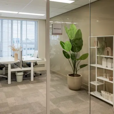 Moderne kantoorruimte op Diemerhof 42 in Diemen met glazen wanden, bureaus, en een plant, ideaal voor werkteams die kantoorruimte willen huren.