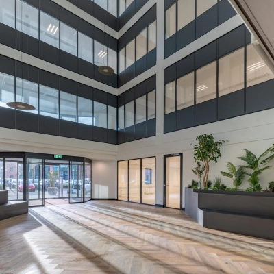 Lichte kantoorentree met houten vloer, grote ramen en moderne plantenbakken in kantoorpand op Wisselwerking 40-48 in Diemen.