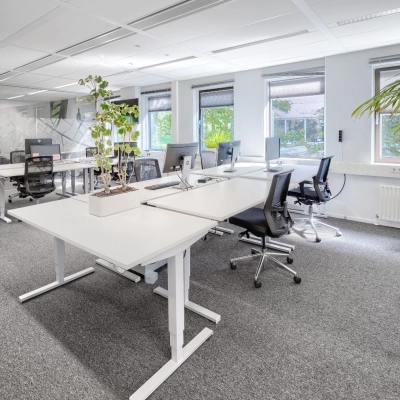 Lichte kantoorruimte met moderne bureaus en ergonomische stoelen, geschikt voor dynamisch werken. Grote ramen zorgen voor natuurlijke lichtinval. Optimaal voor wie een kantoorpand in Diemen wil huren.
