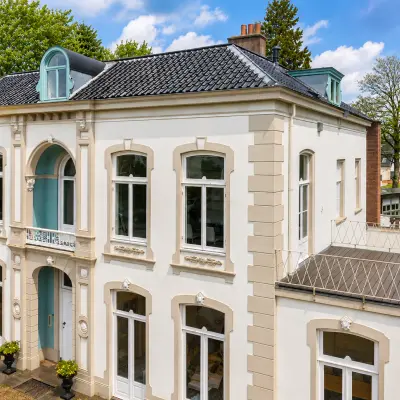 Gevel van een statig kantoorpand aan de Dorpsstraat 77 in Doorn met klassieke details en grote ramen, ideaal voor het huren van een kantoorruimte.
