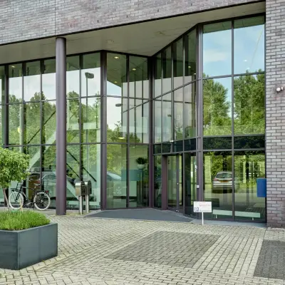Buitenzijde van een modern kantoorpand op Celsiusstraat 34 in Ede, met glazen entree en parkeerplaatsen. Ideaal voor kantoorruimte huren.