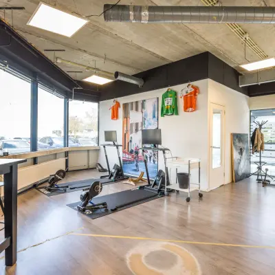 Kantoorruimte te huur op Luchthavenweg 81 bij Eindhoven Airport met moderne inrichting en fitnessapparatuur, ideaal voor een creatieve werkruimte.