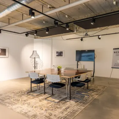 Stijlvol ingerichte kantoorruimte op Luchthavenweg 81, Eindhoven Airport, met een vergadertafel, stoelen en kunstwerken aan de muur. Perfect om te huren voor diverse zakelijke activiteiten.