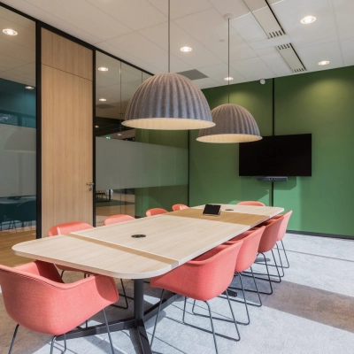 Vergaderruimte in kantoorpand met moderne verlichting, houten tafel en rode stoelen, gelegen op Professor Dr Dorgelolaan 14, Eindhoven Centrum. Ideale plek voor kantoorruimte huren.