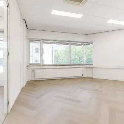 Lichte, open kantoorruimte op Croy 7, Eindhoven De Hurk met grote ramen en stijlvolle laminaatvloer, ideaal voor bedrijfshuur.