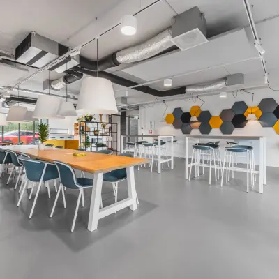 Moderne kantoorruimte op de Hurksestraat 60 in Eindhoven De Hurk met grote tafels, stijlvolle verlichting en kleurrijke muurdecoratie. Ideaal om als kantoor of vergaderruimte te huren.
