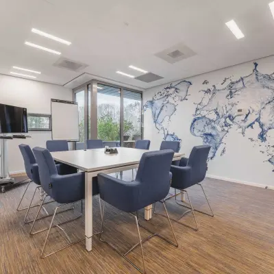 Vergaderruimte in kantoor aan Hurksestraat 60 in Eindhoven De Hurk, met moderne inrichting en wereldkaartmuurschildering, ideaal voor kantoorruimte huren.