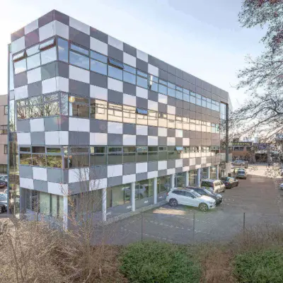 Een modern kantoorpand op Meerenakkerplein 11-20 in Eindhoven De Hurk, met gekleurde panelen en parkeerplaatsen aan de voorkant. Ideale locatie voor wie kantoorruimte wil huren.