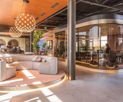 Moderne kantoorruimte huren in kantoorpand op Achtseweg Zuid 159R, Eindhoven Strijp-S, met stijlvolle meubels en grote ramen. Personen werken in een vergaderruimte en open werkplekken.