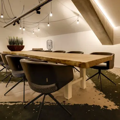 Moderne vergaderruimte in Eindhoven Strijp-S met grote houten tafel, comfortabele stoelen en sfeerverlichting, ideaal voor kantoorruimte huren.