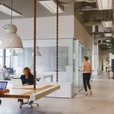 Moderne kantoorruimte in Eindhoven Strijp-S, met gemotiveerde professionals die bezig zijn met werk aan laptops. De inrichting is industrieel met grote ramen en hangende verlichting.