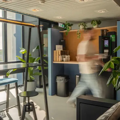 Moderne kantoorpand in Eindhoven Strijp-S met levendig interieur, hoge ramen en een mix van zitopties. Groenvoorziening geeft een frisse sfeer. Ideaal voor kantoorruimte huren.