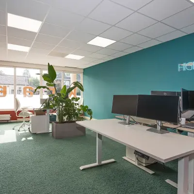 Moderne kantoorruimte op Boddenkampsingel 95 in Enschede met groen tapijt, bureaus met computers en planten. Geschikt voor huur als werkplek in een kantoorpand.