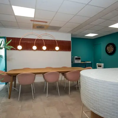 Kantoorruimte op Boddenkampsingel 95 in Enschede met een vergadertafel, roze stoelen en een moderne inrichting. Planten en decoratieve elementen creëren een uitnodigende sfeer.