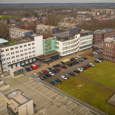 Luchtfoto van het kantoorpand aan de Brouwerijstraat 1 in Enschede met parkeergelegenheid ervoor. Het gebouw is ruim opgezet en biedt mogelijkheden voor kantoorruimte huren.