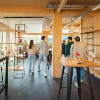 Moderne kantoorruimte huren op Moutlaan 1-23, Enschede, met een lichte inrichting en houten elementen. Mensen voeren zakelijke activiteiten uit in een gemeubileerd interieur.