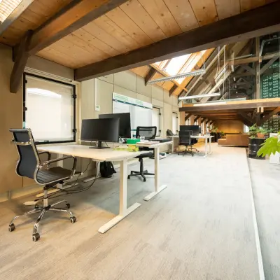 Kantoorruimte huren in Franeker aan de Prins Hendrikkade 3 met een moderne, open indeling. Voorzien van werkstations met bureaustoelen en computerschermen onder een rustiek houten plafond.