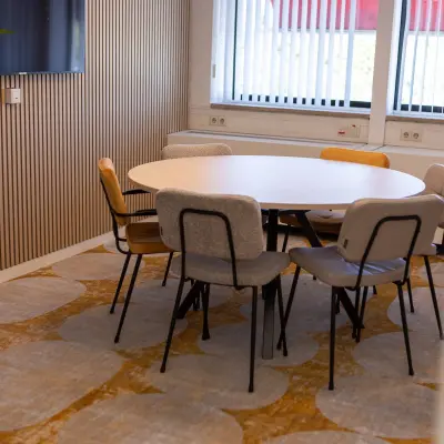 Gezellige vergaderruimte in een kantoorpand op Atoomweg 6B, Groningen met een ronde tafel omringd door diverse stoelen.
