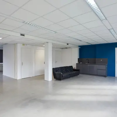 Kantoorruimte op Schweitzerlaan 12 in Groningen met een betonnen vloer en een blauwe accentmuur, geschikt voor huur. De ruimte is nog niet ingericht met kantoormeubilair.