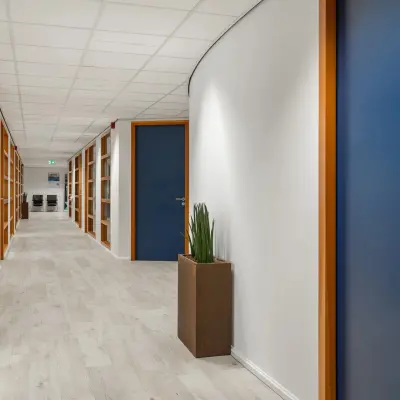 Lange gang met houten plankenvloer en blauwe deuren in een kantoorpand op A. Hofmanweg 5A in Haarlem Waarderpolder, ideale locatie voor kantoorruimte huren.