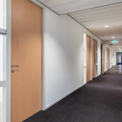 Gang in het kantoorpand op Mollerusweg 84 in Haarlem Waarderpolder, ideaal voor kantoorruimte huren. De gang heeft deuren aan beide zijden en biedt toegang tot verschillende kantoren.