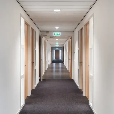 Lange gang in een kantoorpand met witte muren en meerdere gesloten deuren aan beide zijden op Mollerusweg 84, Haarlem Waarderpolder.