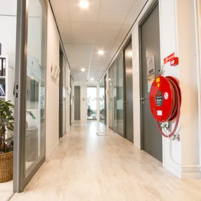 Heldere kantoorruimte op Waarderweg 19 met glazen deuren en een modern interieur. Kantoorunits en een rek met kantoorbenodigdheden langs de muur.