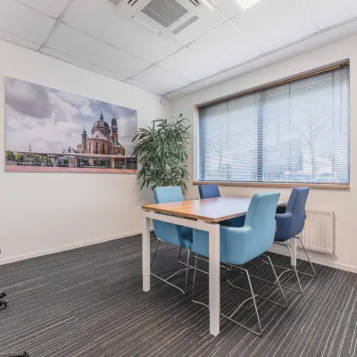 Stijlvolle vergaderruimte in kantoorpand Steenovenweg 5, Helmond. De ruimte is voorzien van moderne stoelen rondom een houten tafel, met uitzicht door een groot raam.