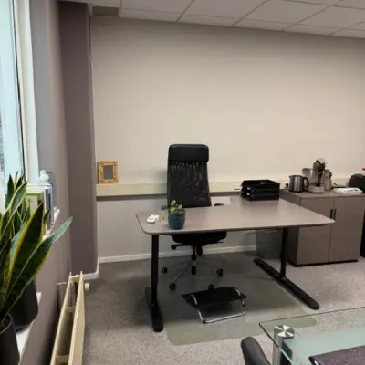 Zicht op een lichte kantoorruimte op Hamerstraat 10, Hengelo, met een bureau, stoel, planten en een kast. Ideaal voor wie kantoorruimte wil huren.