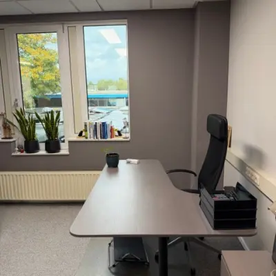 Kantoorruimte huren op Hamerstraat 10, Hengelo. Een strak ingerichte ruimte met bureaus, een comfortabele stoel en uitzicht op de buitenomgeving.