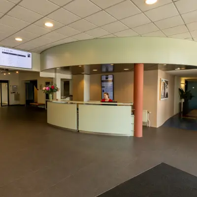 Ontvangstruimte in een kantoorpand op Lansinkesweg 4, Hengelo met een balie en kleurrijke stoelen. Perfect voor kantoorruimte huren, met een gastvrije sfeer.