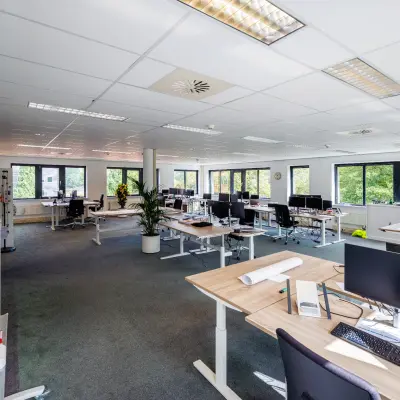 Moderne kantoorruimte met ruime opstelling van bureaus en computerschermen, veel natuurlijk licht en groene elementen aan de Welbergweg 60 in Hengelo. Geschikt voor wie kantoorruimte wil huren.