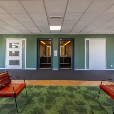 Kantoorruimte huren aan Franciscusweg 219 in Hilversum met een moderne entree, groene vloerkleed en stoelen.
