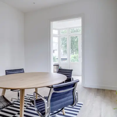 Lichte kantoorruimte op Graaf Florislaan 40, Hilversum met houten tafel en stoelen, geschikt voor zakelijke activiteiten zoals vergaderingen.
