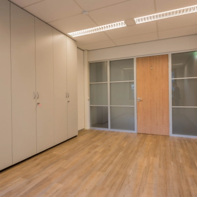 Onverharde kantoorruimte op Mozartlaan 25, Hilversum, met houten vloer en inbouwkasten, ideaal voor wie een kantoorpand wil huren. Geen meubilair aanwezig, klaar voor eigen inrichting.