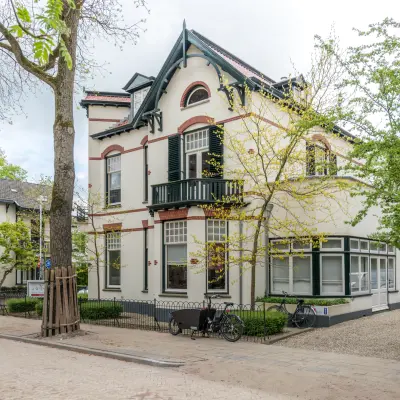 Kantoorpand aan de Oude Enghweg 8 in Hilversum met een karaktervolle gevel en omliggende groene bomen. Ideaal voor kantoorruimte huren in een rustige omgeving.