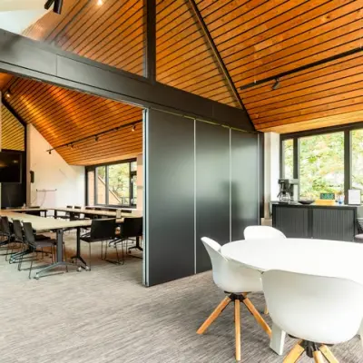 Ruime en lichte kantoorpand op Steijnlaan 16, Hilversum met moderne inrichting en houten accenten, ideaal voor kantoorruimte huren met open werkplekken en een vergadertafel bij het raam.