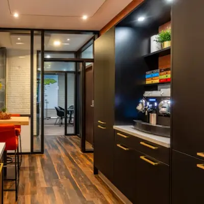 Moderne kantoorruimte met houten vloeren en strakke afwerking op Steijnlaan 16, Hilversum. De ruimte is gemeubileerd met tafels en stoelen, ideaal voor kantoorruimte huren. Een glazen wand scheidt verschillende werkruimtes.