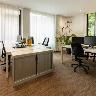 Gemeubileerd kantoor met bureaus en computers, geschikt voor kantoorruimte huren op Steijnlaan 16, Hilversum. Licht en modern design met kunst aan de muur.