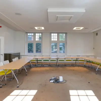 Kantoorruimte huren in Hilversum met een lichte vergaderruimte, voorzien van tafels, stoelen en een tapijtvloer. Ideaal voor zakelijke bijeenkomsten.