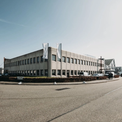 Grijs kantoorpand aan de Meidoornkade 22 in Houten met parkeerplaatsen en vlaggenstokken aan de voorzijde.