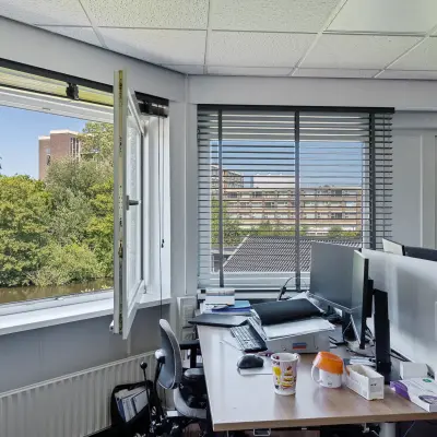 Lichte kantoorruimte met uitzicht op groen, geschikt voor kantoorruimte huren in Leeuwarden, Ouddeelstraat. Werkplekken voorzien van bureaus en computers.