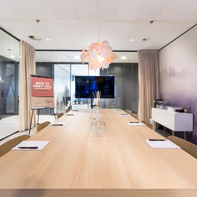 Ruime, moderne vergaderruimte in een kantoorpand op Bargelaan 200, Leiden, met houten tafel, stoelen en glazen wanden. Perfecte plek voor kantoorruimte huren.
