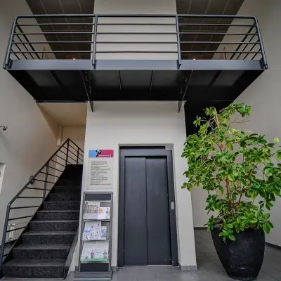 Entree van het kantoorpand op Fruitweg 22 in Leiden met een lift, trap en grote plant. Ideaal voor wie kantoorruimte wil huren.