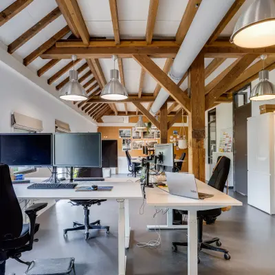 Lichte kantoorruimte aan de Hamersveldseweg 120 in Leusden, met houten balken, bureaus, computers en stoelen, ideaal om een kantoor te huren.