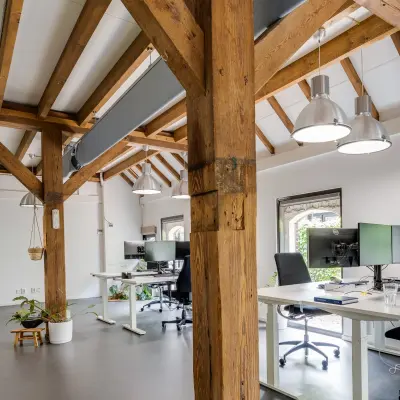 Kantoorruimte huren in Leusden met zichtbare houten balken en moderne werkplekken. Ruim en licht, met ergonomische bureaus en stoelen. Ideaal voor productiviteit.